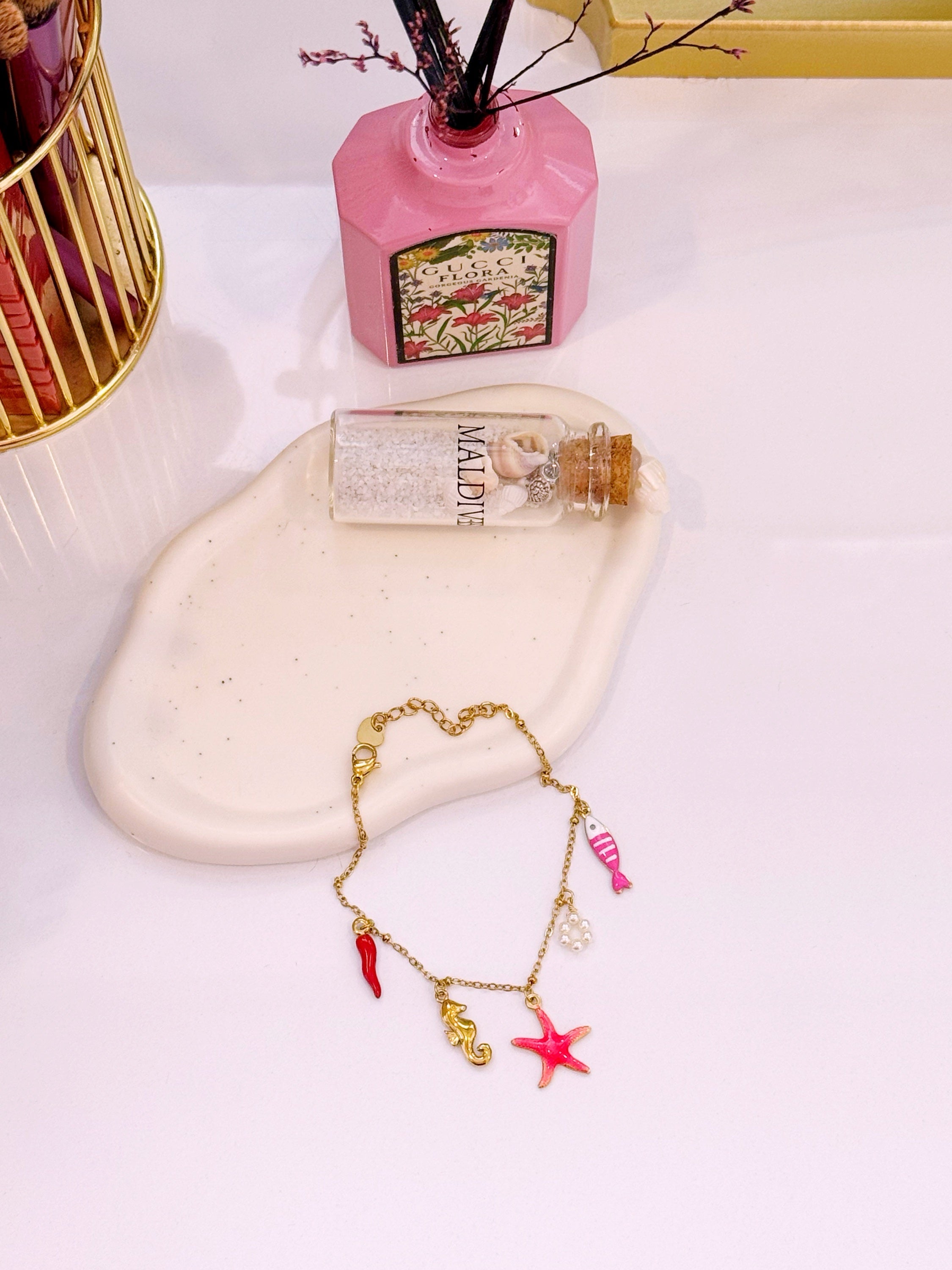 Pulseira com estrela do mar rosinha e vários pendentes | Dourado