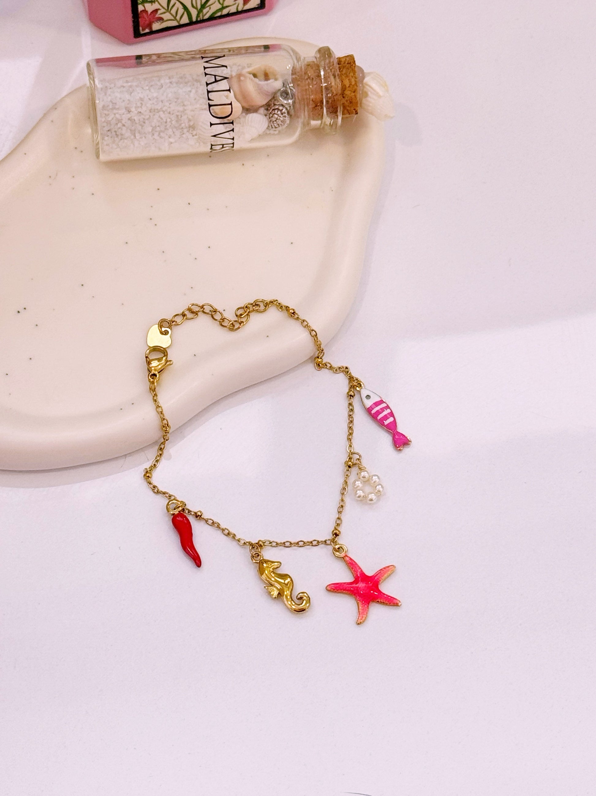 Pulseira com estrela do mar rosinha e vários pendentes | Dourado